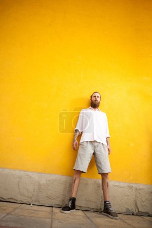Photo for Cool looking bearded guy on yellow wall in outside fashion shooting - Royalty Free Image