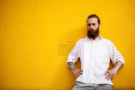 Photo for Cool Tattooed bearded hipster on yellow wall posing outdoor - Royalty Free Image