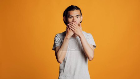 Foto de Confident hipster guy doing three wise monkeys sign on camera, using body language. Modern carefree adult expressing dont look, dont speak and dont hear gesture in studio. - Imagen libre de derechos