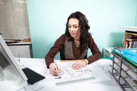Photo for Woman on working desk with blueprints in front of her. Working on new projects. Architecture and design - Royalty Free Image