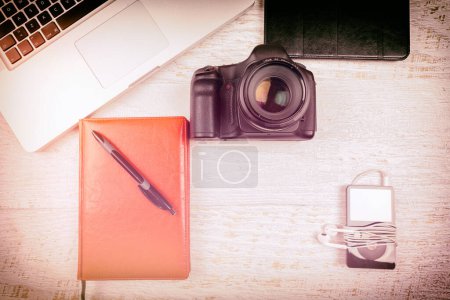 Téléchargez les photos : Sur la photo supérieure de l'appareil photo et ordinateur portable dans un ton vintage sur fond en bois - en image libre de droit