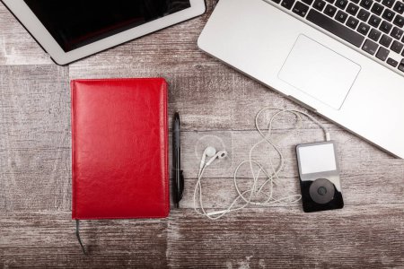 Photo for Music player, laptop and writing notebook from above view on a wooden background - Royalty Free Image