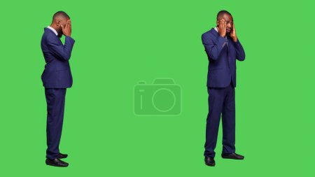 Photo for Male entrepreneur dealing with headache over full body green screen background, feeling ill in studio. Young startup manager in suit suffering from migraine and being sick, hurt businessman. - Royalty Free Image