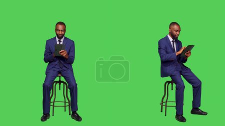 Photo for Young entrepreneur scrolling through online website, using digital tablet over full body green screen background. Businessman browsing on internet network web page, formal office suit. - Royalty Free Image