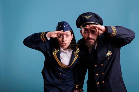 Photo for Portrait of airplane capitan and flight attendant couple looking at camera, medium shot. Aircrew team wearing flight uniform while standing in studio with blue background - Royalty Free Image