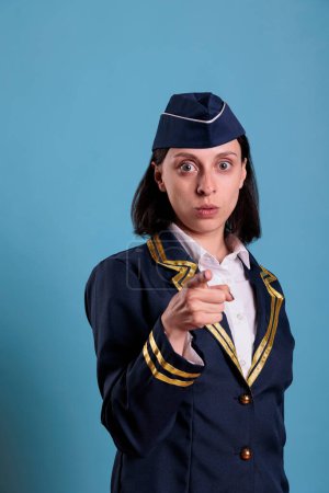 Photo for Young serious flight attendant pointing at camera with finger, aviation academy recruitment concept. Confident airlines stewardess in professional uniform portrait front view - Royalty Free Image