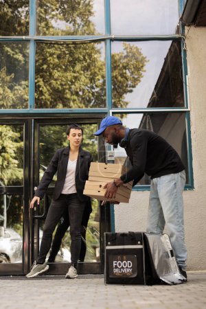 Foto de Cliente que recibe la pila de cajas de pizza, mensajero sacando orden de mochila térmica al aire libre. Servicio de reparto de comida, pizzería afroamericana repartidor celebración comida para llevar - Imagen libre de derechos