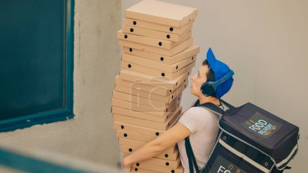 Photo for Clumsy food courier trying to catch falling pizza boxes, acting scared and running from client front door after dropping fastfood delivery meal. Afraid carrier with bad service. Handheld shot. - Royalty Free Image