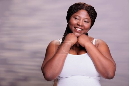 Photo for Smiling african american body positive woman holding hands under chin portrait. Curvy beautiful lady feeling happy, showing optimistic lifestyle and expressing positive emotions - Royalty Free Image
