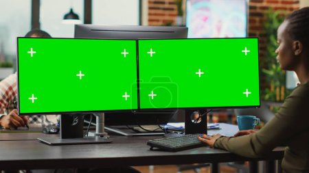 Photo for Young digital creator looking at computers with greenscreen, working on professional monitor with isolated display. Woman 3d editor analyzing blank chroma key mockup copyspace. - Royalty Free Image