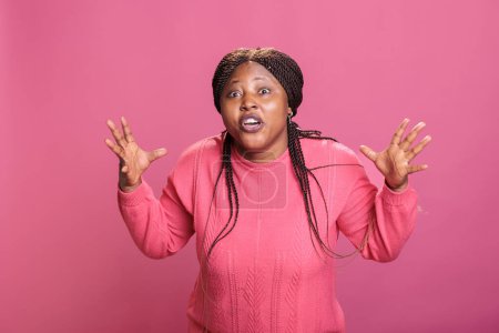 Foto de Modelo afroamericano sentirse frustrado y agresivo mientras posando en el estudio sobre fondo rosa. Furiosa mujer estresada con colapso mental que muestra una reacción desagradable. - Imagen libre de derechos