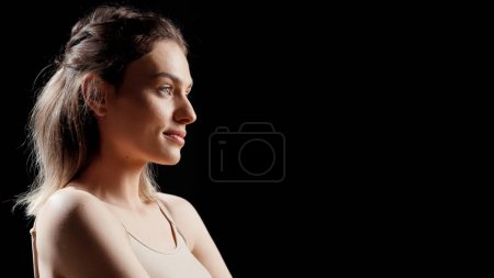 Photo for Radiant gentle girl promoting body cream on camera, filming beauty ad campaign and applying moisturizer and neck and shoulders. Beautiful model using glowing serum and advertising product. - Royalty Free Image