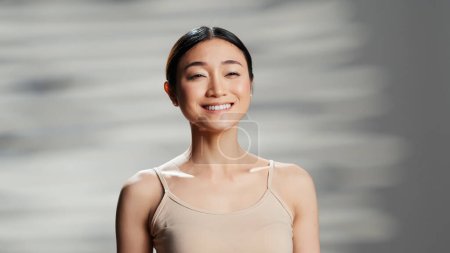 Photo for Beautiful person creating skincare cosmetics ad, posing with glamour and tenderness on camera. Asian woman promoting beauty products for radiant luminous skin, body acceptance. - Royalty Free Image