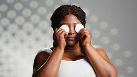 Photo for African american girl using cotton pads on camera, using toner and cleanser as beauty routine. Promoting skincare and bodycare, beauty products for radiant appearance. Glowing woman. - Royalty Free Image