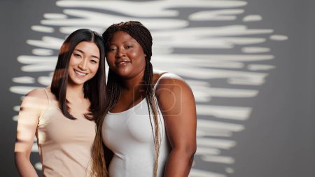 Photo for Smiling beauty models hugging and looking at camera, expressing positive emotions and bodycare. Beautiful interracial young women with different body types and skintones posing. - Royalty Free Image