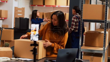 Photo for Depot employee filming marketing video on phone, using social media streaming platform for advertising. Young female employee recording merchandise promotion for online ad campaign. - Royalty Free Image