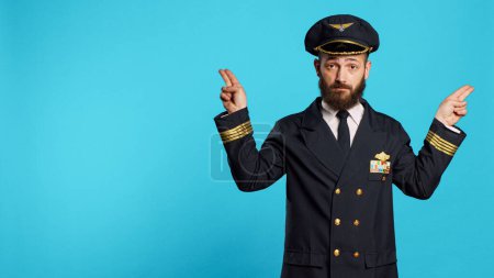 Photo for Young serious airliner doing landing signals for planes, helping other pilots to arrive on ground. Aircrew captain showing air gestures with hands on camera, professional occupation. - Royalty Free Image