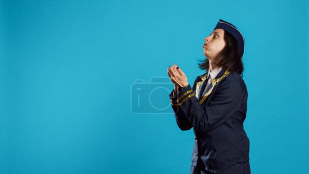 Photo for Young adult dressed as air hostess applauding, clapping hands and feeling positive about aviation and commercial flights. Smiling stewardess doing standing ovation gesture and cheering. - Royalty Free Image