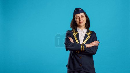 Photo for Smiling young woman working as air hostess, wearing flying uniform and posing with confidence. Cheerful stewardess preparing for commercial flight, working in aviation industry. - Royalty Free Image