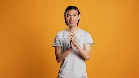 Photo for Asian man clapping hands on camera, smiling and showing positive emotions. Cheerful carefree guy applauding and cheering for something, saying congratulations. Standing ovation gesture. - Royalty Free Image