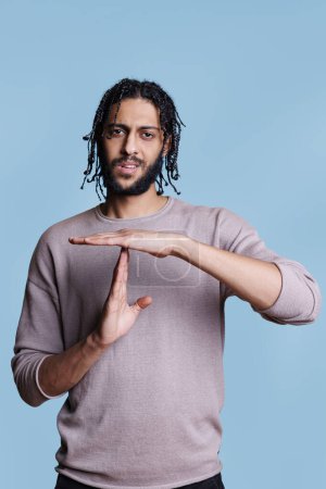Photo for Arab man showing timeout gesture, making pause symbol with hands portrait. Young person doing interruption sign with arms, taking break from communication and looking at camera - Royalty Free Image