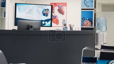 Photo for Wheelchair in disability friendly lobby used for physical recovery on health care insurance, empty facility waiting area. Hospital reception front desk with seats and medical papers, checkup reports. - Royalty Free Image