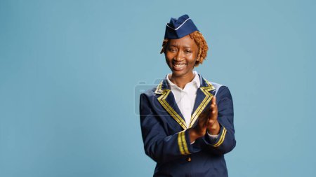 Photo for Female airliner applauding on camera, cheering and doing standing ovation. Cheerful smiling woman dressed as air hostess clapping hands, having professional aviation occupation. - Royalty Free Image