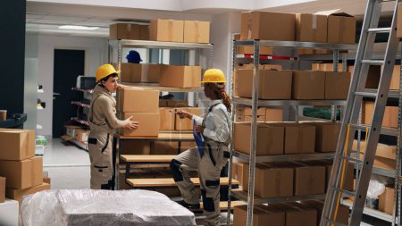 Photo for Diverse women checking boxes of merchandise in depot, arranging industrial goods in packages. Young employees working with stockroom products in storage room, manufacturing job. Tripod shot. - Royalty Free Image