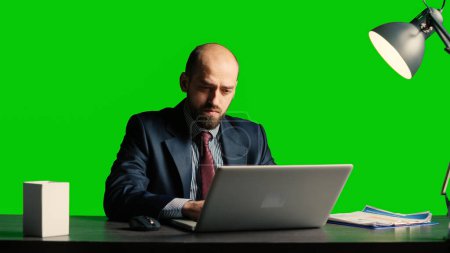 Foto de Businessman over greenscreen feeling tired and stressed, sitting laid back at desk. Team leader working over chroma key backdrop with isolated mockup template, exhausted adult. - Imagen libre de derechos