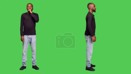 Photo for Young adult feeling tired and yawning on camera, falling asleep standing over full body green screen backdrop. Male person being exhausted and sleepy in studio, stressed model. - Royalty Free Image