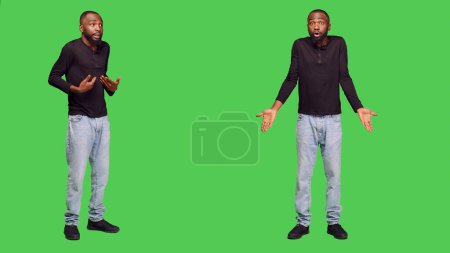 Photo for Angry person having argument with someone on camera, feeling furious and being in conflict. Young displeased man fighting and feeling aggressive, standing onver full body green screen. - Royalty Free Image