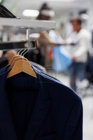 Photo for Jackets hanging on rack in trendy clothing store for sale with blurred background. Casual modern blazers from new collection on hangers in department shopping mall close up selective focus - Royalty Free Image