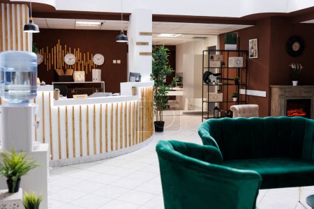 Empty hotel reception with lounge area and front desk used for check in and check out, resort entrance with service bell. Luxury space with counter used for booking rooms, marble floors.