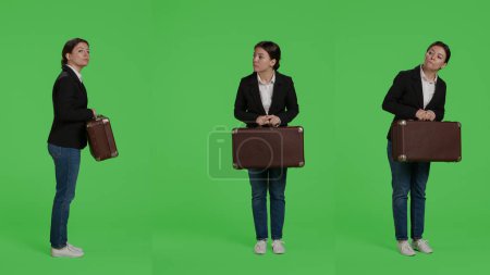 Photo for Office employee carrying vintage suitcase wearing corporate suit, holding briefcase or travel bags over full body greenscreen backdrop. Company worker with baggage preparing to leave. - Royalty Free Image