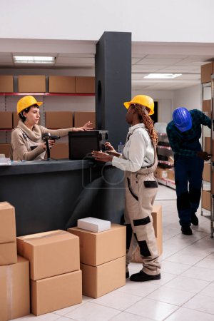 Photo for Warehouse worker putting customer order on counter for scanning and packing. Post office storage employees preparing suitcase for dispatching at reception desk and using bar code scanner - Royalty Free Image