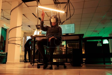 Téléchargez les photos : Un pirate anonyme faisant un geste de main dans la réalité augmentée, attaquant un serveur de bases de données, cybercriminalité. Simulation de piratage du système informatique, hameçonnage d'informations, programmation de logiciels malveillants en ar - en image libre de droit