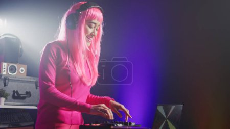 Photo for Asian performer mixing electronic sound using mixer console, dancing and having fun in club with fans during performance. Dj artist performing techno music using professional audio equipment - Royalty Free Image