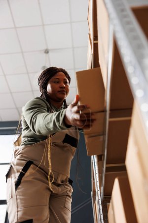 Photo for Storage room worker employee taking out cardboard boxes, packaging customer order before shipping products in warehouse. Stockroom employee wearing industrial overall in storehouse - Royalty Free Image