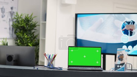 Photo for Laptop with greenscreen display at desk placed on empty registration counter in waiting area reception. Isolated copyspace on screen in hospital lobby, blank chroma key mockup. - Royalty Free Image