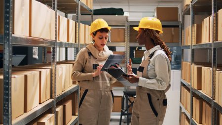 Photo for Diverse employees working on inventory and logstics to plan transportation and delivery, industrial shipment. Female workers examining products and goods on warehouse shelves. - Royalty Free Image