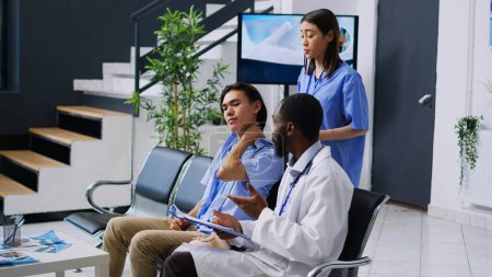 Photo for Orthopedist medic and nurse helping asian patient to take off cervical neck collar during checkup visit consultation in hospital waiting room. Young adult receiving medicine support and service - Royalty Free Image