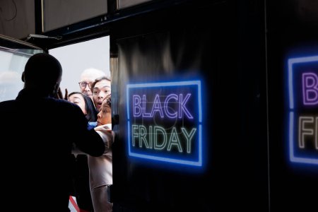 Photo for Mad obsessed crowd of people shoppers trying to open shopping mall entrance door, fighting with security guard. Crazy consumers breaking into store, rushing to get best Black Friday deals - Royalty Free Image