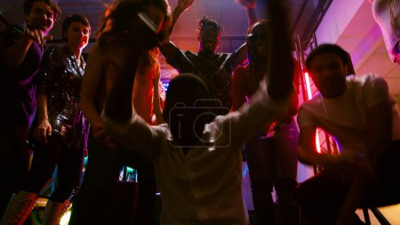 Foto de Punto de vista de los jóvenes bailando en la fiesta, mostrando movimientos de baile funky en cámara en la discoteca. Grupo de hombres y mujeres de fiesta en discotecas de música en el club nocturno, divertirse. Disparo de mano. - Imagen libre de derechos