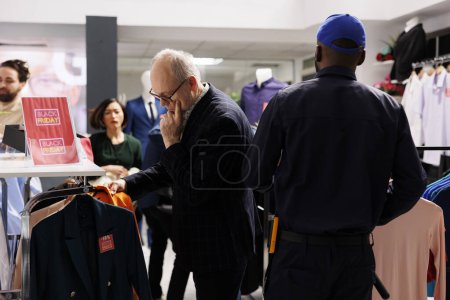 Photo for Pensive mature man shopping in fashion mall on Black Friday. Senior male costumer standing in crowded clothing store buying clothes during seasonal sales, looking through hangers with jackets - Royalty Free Image