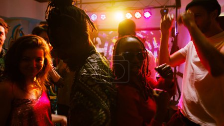 Photo for POV of cheerful persons enjoying dance party at nightclub, having fun together on funky music. Young people jumping and partying on dance floor, dancing under spotlights. Handheld shot. - Royalty Free Image