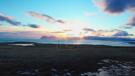 Foto de Paisaje ártico de playa de arena negra en iceland, paisaje escandinavo de colinas nevadas y agua fría. Majestuoso paisaje nórdico en la costa con mareas y olas oceánicas. Disparo de mano. - Imagen libre de derechos