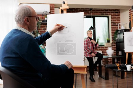 Photo for Senior man student sitting at easel using pencil drawing on canvas, active retiree learning how to draw with teacher in art group, enjoying creative activities in relaxed peaceful atmosphere - Royalty Free Image