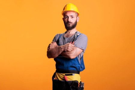Photo for Confident male contractor holding pair of pliers to work on house renovation, standing in studio. Construction worker foreman using pliers and refurbishment tools, industrial engineering. - Royalty Free Image