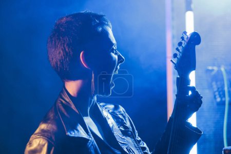 Photo for Musician performer holding electric guitar playing heavy metal song in studio preparing rock performance for grunge concert. Beautiful guitarist working at punk album, checking instrument sound - Royalty Free Image
