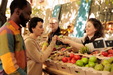 Diversas parejas hombre y mujer que compran productos naturales frescos en el mercado de agricultores, mirando productos biológicos. Vendedor local sonriente de pie detrás de pie frutas y verduras, vender alimentos saludables.